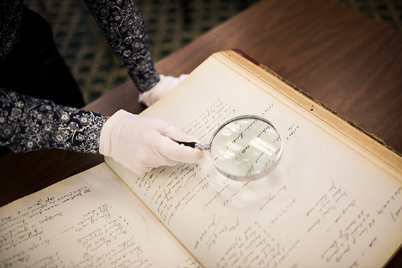 A researcher holds a magnifying glass over historical records